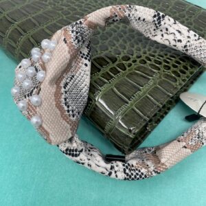 Flat lay of a snake print and pearl headband on top of a green animal print notebook.