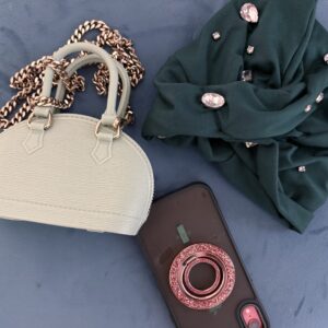 Turban with large stones with flat lay next to a purse and phone.