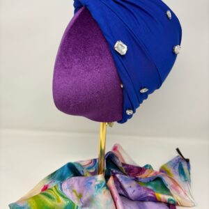 Royal blue fabric on top of a mannequin head facing side profile to the left to show stone embellishments.
