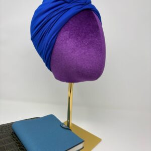 Royal blue fabric on top of a mannequin head facing side profile to the right.