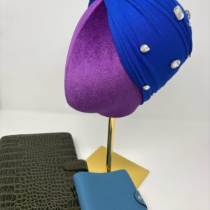 Royal blue fabric on top of a mannequin head facing side profile to show stone embellishments.