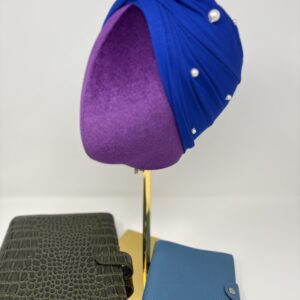 Royal blue fabric on top of a mannequin head side profile to show pearl embellishments.