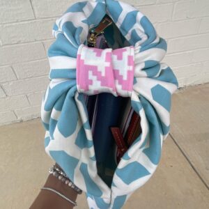 Hand holding up a cloth pattern bag with items inside.