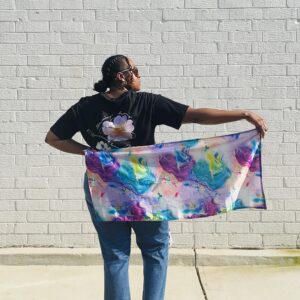 Woman standing looking to the side holding out a piece of fabric behind her.